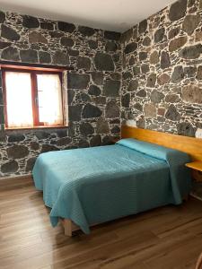 a bedroom with a bed and a stone wall at Casa rural con baño adaptado y piscina en Mogán in Mogán