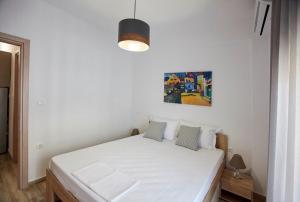 a white bed in a room with a painting on the wall at MG apartments in Alexandroupoli