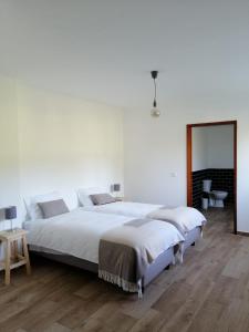 a white bedroom with two beds and a mirror at Casa do Coura in Caminha