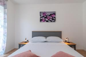 um quarto com uma cama branca e 2 almofadas em Apartman Galeb em Trogir