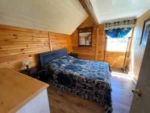 1 dormitorio con 1 cama en una cabaña de madera en Beach & Breeze Cottages, en Stanley Bridge