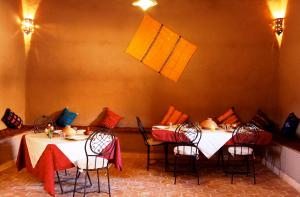 a dining room with two tables and chairs with colorful pillows at Riad Nomad in Foum Mharech
