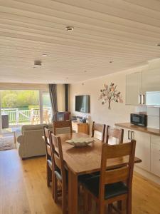 cocina y comedor con mesa de madera y sillas en Grange Lodge en South Cerney