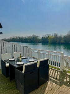 a table and chairs on a deck with a view of a river at Grange Lodge in South Cerney
