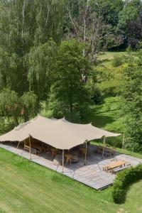 une grande tente avec des tables et des bancs dans un champ dans l'établissement Glamping Chateau de La Chapelle, à Anthisnes