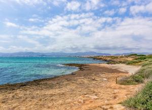 a beach with the ocean and mountains in the background at Villa Cala Estancia Mercedes by PriorityVillas in Palma de Mallorca