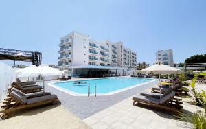 a swimming pool with lounge chairs and umbrellas at Kapetanios Bay Hotel Protaras in Protaras