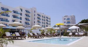 ein Pool mit Stühlen und Sonnenschirmen neben einem Hotel in der Unterkunft Kapetanios Bay Hotel Protaras in Protaras