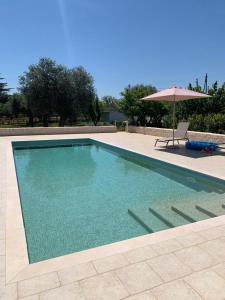 - une piscine avec une table et un parasol dans l'établissement Il Villino di GRAZIO, à Monopoli