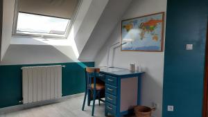 Cette chambre dispose d'un bureau bleu et d'une fenêtre. dans l'établissement La Ménagerie, à Maigné