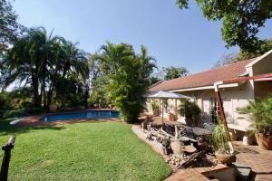 un patio trasero con piscina y una casa en Wonderfully spacious two bedroom cottage in a quiet secluded area of town, on the edge of the bush - 1998, en Victoria Falls