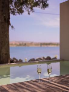 dos copas de vino sentadas en una mesa junto a una piscina en GAIA Alaçatı BY THE SEA - Adult Only, en Cesme