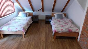 two beds in a small room with wooden floors at Apartments Alibasic in Dubrave Gornje