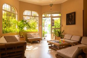 a living room with couches and a table and windows at Le Lodge des Almadies in Dakar