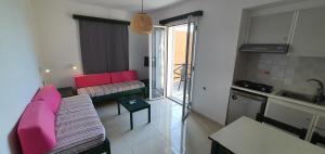 a living room with pink furniture and a kitchen at Stella Apartments in Kokkini Khanion