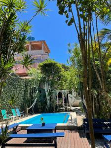 a pool with a table and chairs and palm trees at Pousada Bicho do Mar in Arraial do Cabo