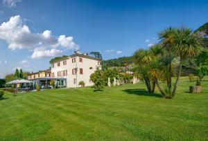een groot wit huis met palmbomen in een veld bij Hotel Albergo Villa Marta in Lucca