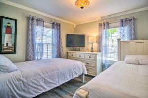 a bedroom with two beds and a tv and windows at Wareham Cottage with Deck, Walk to Swifts Beach in Wareham