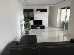 a living room with a black couch and a tv at Apartmány Dimitra 2 in Štúrovo