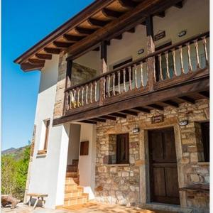 a building with a balcony and a wooden door at Apartamentos rurales El Torneru in Piloña