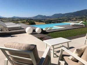 eine Terrasse mit Stühlen, einem Tisch und einem Pool in der Unterkunft Serre Alte Landscape Luxury Rooms in Matelica