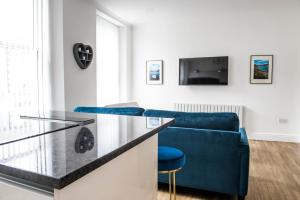 un salon avec un canapé bleu et une télévision dans l'établissement Osprey Residence - Smart & Stylish Apartment in the Heart of Kendal, à Kendal