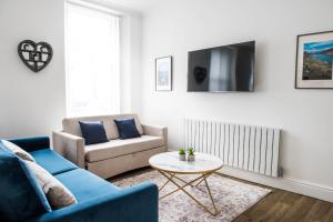 ein Wohnzimmer mit einem Sofa und einem Tisch in der Unterkunft Osprey Residence - Smart & Stylish Apartment in the Heart of Kendal in Kendal