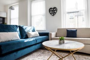 een woonkamer met een blauwe bank en een tafel bij Osprey Residence - Smart & Stylish Apartment in the Heart of Kendal in Kendal