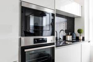 a microwave oven in a kitchen with a sink at Osprey Residence - Smart & Stylish Apartment in the Heart of Kendal in Kendal