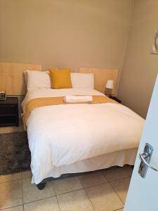 a large bed with white sheets and yellow pillows at Beach Hive 1 in Swakopmund