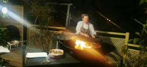 een man die eten kookt op een barbecue grill bij Le Clos des Lodges in Bernay