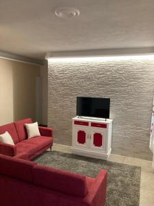 sala de estar con sofá rojo y TV de pantalla plana en La Tillanzia, en Dolceacqua
