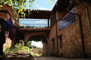 an old stone building with a bridge over a street at Casa Rural - Apartamentos Atuvera in Villanueva de la Vera
