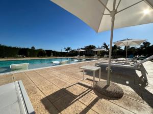 eine Terrasse mit einem Sonnenschirm, einer Bank und einem Pool in der Unterkunft Dependance di Villa Melissa in Parabita