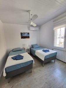 1 dormitorio con 2 camas y ventilador de techo en Torredembarra cosy, well equipped house, 5 min. from the beach en Torredembarra