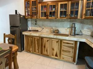cocina con armarios de madera y nevera en Robin Hood Guest House, en Port Antonio