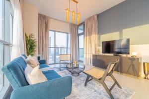 a living room with a blue couch and a tv at Spacious Art Deco Apt with Burj & Canal Views in Dubai