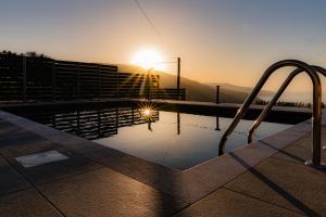 a swimming pool with a sunset in the background at Villa Athina in Anomeriá