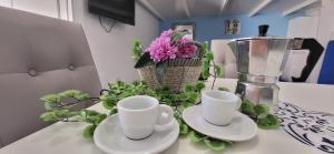 a counter with two white cups and plates and flowers at Monolocale Love Loft in Tropea