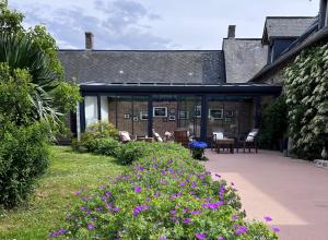 a garden with purple flowers in front of a building at Le Pré Marin in Sotteville-sur-Mer