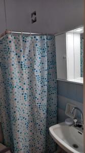 a bathroom with a blue shower curtain with a sink at Studio Vasilis in Ýpsos