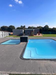 a blue swimming pool with a house in the background at Mafini Villa in Centurion