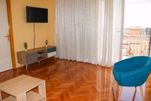 een woonkamer met een blauwe stoel en een televisie bij Jure Bili in Zadar