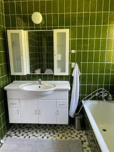 Baño de azulejos verdes con lavabo y bañera en Feriehus-Gammel Byvej, Vrensted, en Løkken