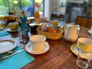潘蓬的住宿－La Corne de Cerf, Forêt de Brocéliande，一张木桌,上面有杯子和盘子,还有一篮面包