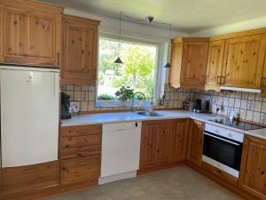 a kitchen with wooden cabinets and white appliances at Feriehus-Gammel Byvej, Vrensted in Løkken +48 photos