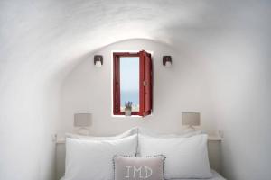 a mirror above a bed with white pillows at Casa Terra Vedema Oia - Privacy - Plunge Pool & Panoramic Sunset Terrace in Oia +67 photos