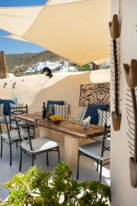 a table and chairs on a patio with an umbrella at Casa Terra Vedema Oia - Privacy - Plunge Pool & Panoramic Sunset Terrace in Oia