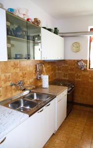 a kitchen with white cabinets and a sink at Artistic summer house Marinovic with garden&BBQ in Supetar