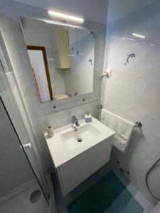 La salle de bains blanche est pourvue d'un lavabo et d'un miroir. dans l'établissement Oliver, à Ankaran